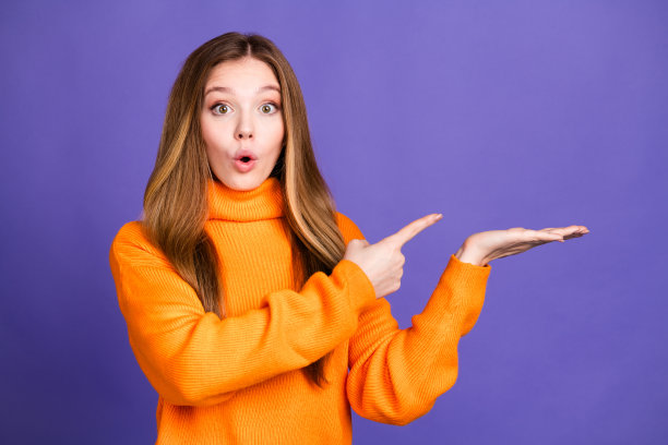 年轻女孩的肖像照片，金色头发，可爱，开心，惊讶的微笑，手中拿着产品，背景为紫色。图片下载