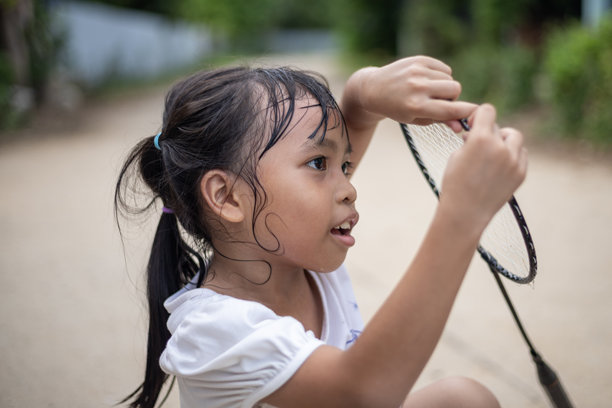 一个年轻女孩手持网球拍，正看着镜头。图片下载