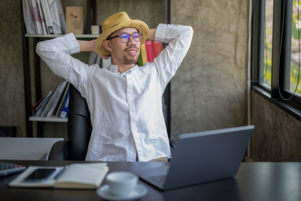 穿着休闲服的商人在办公室椅子上靠着，双手放在头后，休息片刻。图片下载