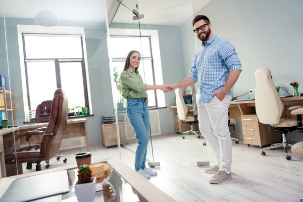 两个商人男女握手的照片在现代职场工作站进行交易图片下载