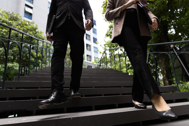 两个人的两条腿在城市里走上楼的特写。商业和人的概念。尝试和成功的主题。图片下载