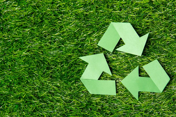 一个绿色回收符号在一个郁郁葱葱的草地背景与复制空间。图片下载