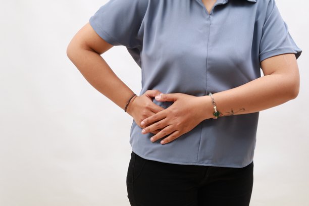 特写镜头：女性手握住右侧腹部，感到右侧腹痛。背景为白色。图片下载