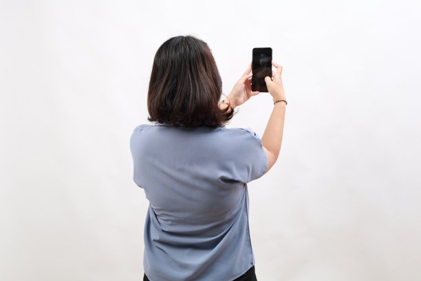 亚洲女性企业家从后面拍摄手机照片。背景为白色。图片下载