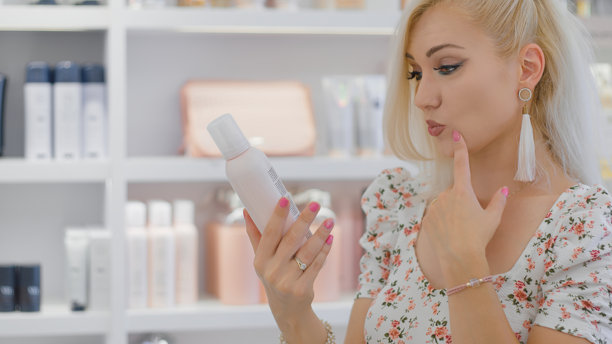 女性在美容店认真查看护肤品瓶子图片下载