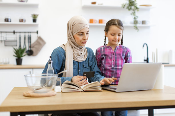 母女俩在厨房用笔记本电脑网购图片下载