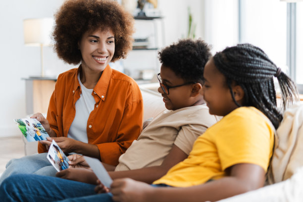 快乐的非裔美国女性和小孩们在舒适的沙发上观看家庭照片图片下载