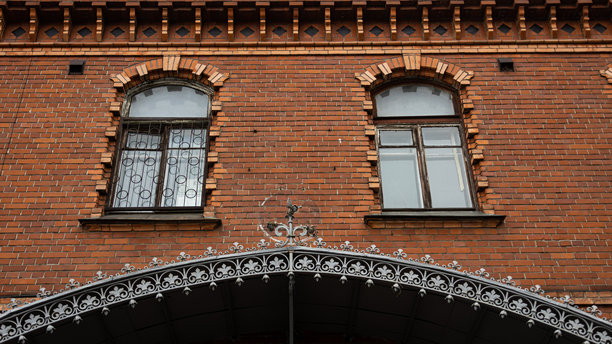 一座砖砌建筑，配有优雅的拱形窗户和铁艺拱门图片下载