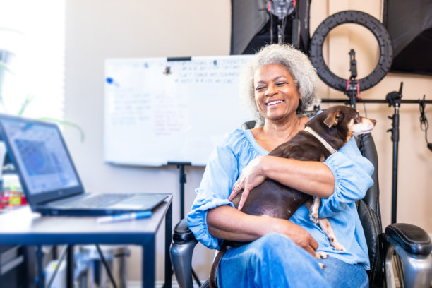 一位年长的黑人女性与她的狗在家中办公室里图片下载