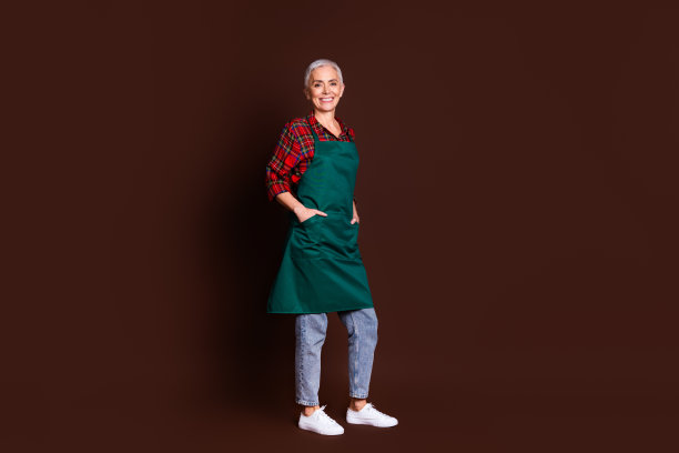 自信的老年女士穿着红色格子衬衫，背景为棕色，完整身影照片图片下载