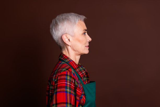 可爱的老年女士穿着红色格子衬衫，背景为棕色，个人头像照片。图片下载