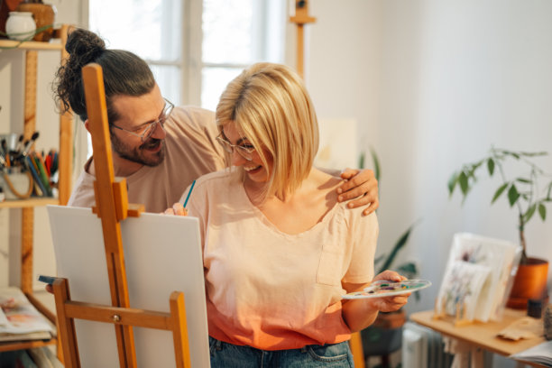 热爱艺术的情侣在工作室里拥抱并在画架上作画。图片下载