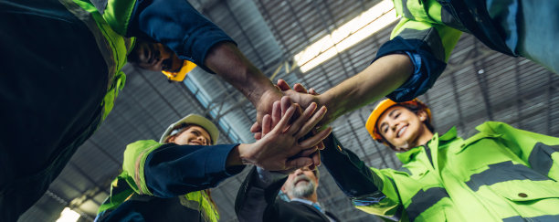 一群成功的工作人员用手相互搭在一起，展示团结。照片中，工头的手在最上面，象征着团队合作。团队合作概念。图片下载