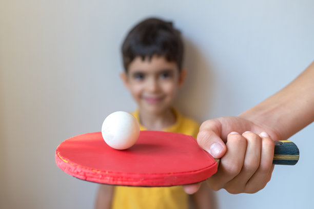 小男孩想打乒乓球。爱好，梦想，运动。学习的概念。网球拍在爸爸或老师的手中。图片下载