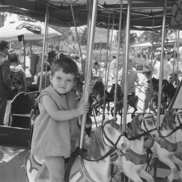 60年代的照片：小女孩在游乐园的旋转木马上骑行图片下载