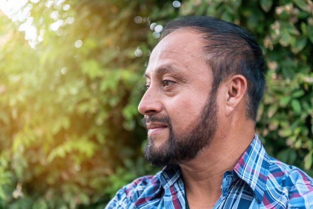 一位西班牙裔成熟男性在自家后院摆姿势，目光投向远方的头像照片图片下载