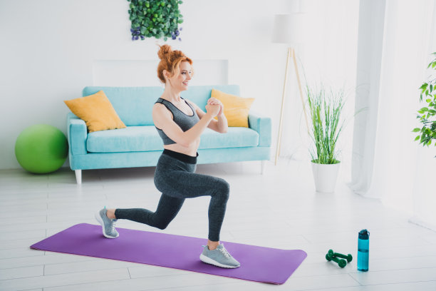 全身照片，漂亮的年轻运动女性在家里的健身房练习弓步，使用健身垫。图片下载