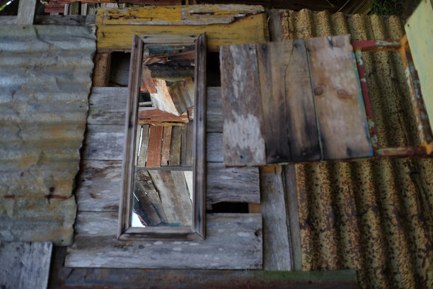 一面位于老旧建筑中的镜子，周围是生锈的锌墙。图片下载