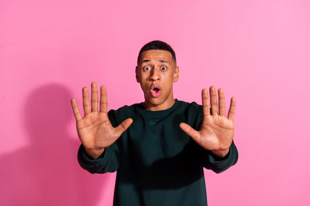 照片中的帅气紧张的家伙穿着运动衫，露出手臂手掌，要求停止空白的空间孤立的粉红色背景图片下载