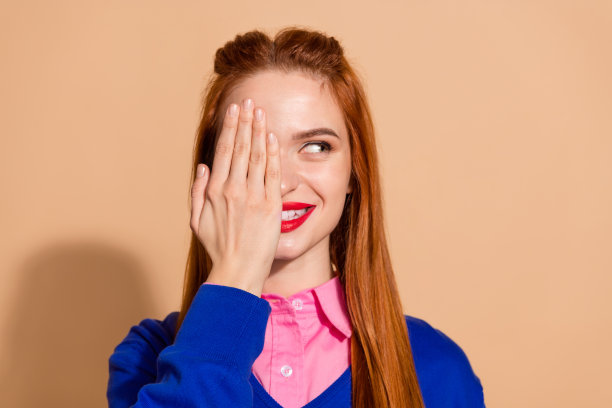 照片中滑稽狡猾的女士穿着粉色衬衫，手臂遮住眼睛，看起来空无一物，孤立的米色背景图片下载