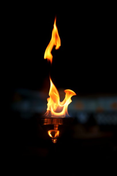 一张迷人的照片，展示了一只装满酒精的马提尼酒杯，上面燃烧着跳动的火焰。图片下载