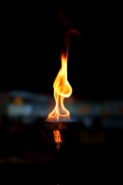 一张迷人的照片，展示了一只装满酒精的马提尼酒杯，上面燃烧着跳动的火焰。图片下载