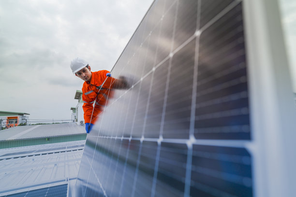 工程师检查太阳能电池板或光伏电池的施工，使用电子设备。工业可再生能源的绿色电力。工人在塔楼屋顶工作。图片下载