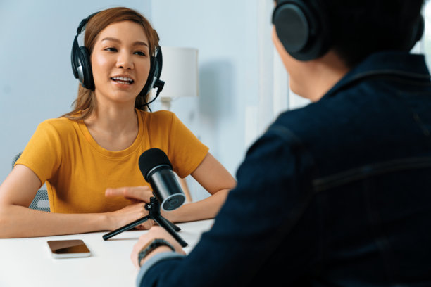 戴着耳机的广播影响者主持人与女性进行社交在线采访。信息高速公路。图片下载
