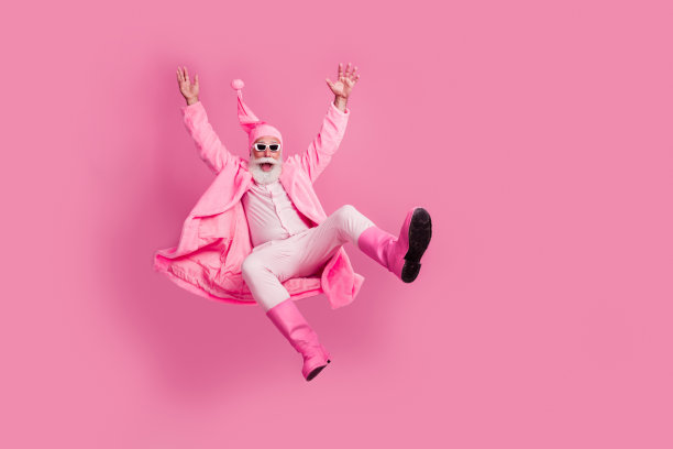 穿着浴袍和靴子的兴奋老年人从粉色背景的空中坠落的全身照片图片下载