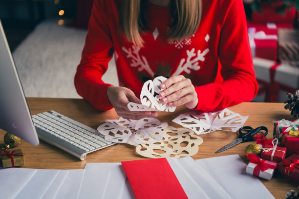裁剪的照片，漂亮的年轻女孩穿着圣诞服装，享受现代舒适的圣诞派对装饰，室内公寓里剪纸雪花。图片下载