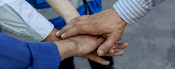 一群成功的工作人员用手相聚展示团结。照片中，工头的手放在上面，象征着团队合作。团队合作概念。图片下载