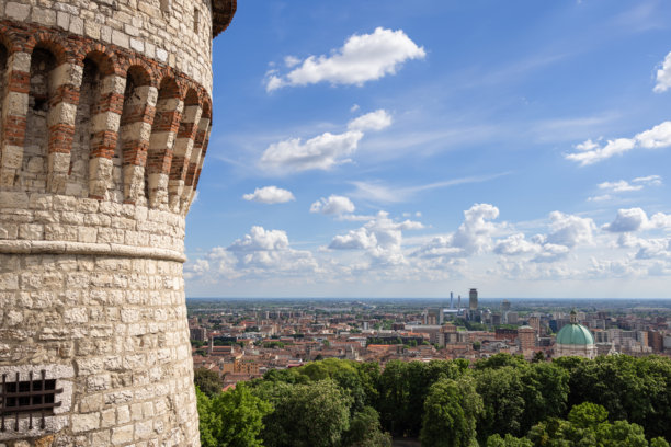 意大利布雷西亚城堡俯瞰老城区，展现了大教堂的圆顶和商业区。监狱塔在左侧框住了这一景象，天空晴朗，湛蓝。图片下载