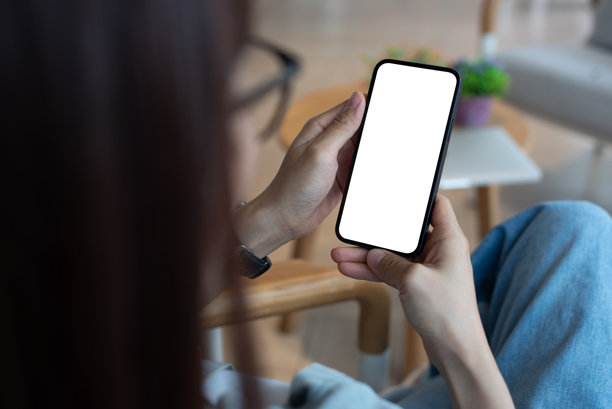 手机模型，空白白色屏幕。女性手持手机在咖啡店。女性时尚人士使用智能手机，空白白色屏幕模板用于产品广告和移动应用设计。图片下载