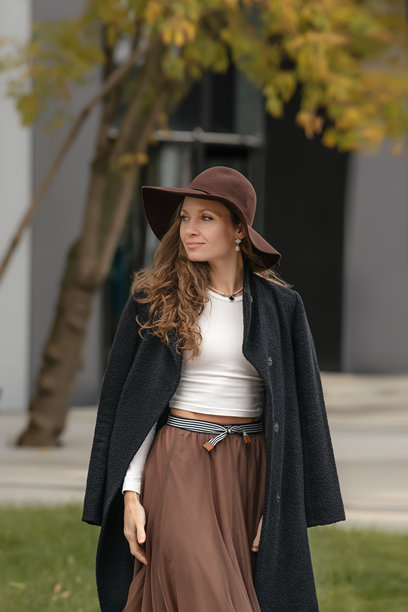 一位成熟的女性在秋季穿着长外套、薄纱裙和宽边帽。图片下载