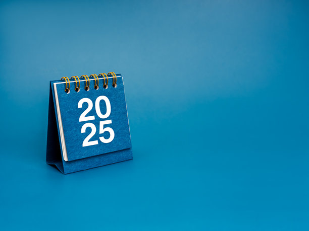 2025年新年快乐的背景。白色2025数字在小台历封面站在蓝色背景与复制空间，最小的风格。商业计划议程、使命和成功目标概念。图片下载