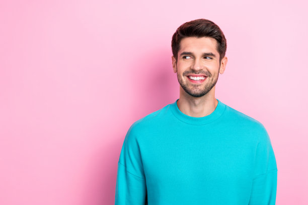 吸引人的年轻男性肖像，穿着时尚的蓝色服装，目光专注于空旷的空间，背景为粉色。图片下载