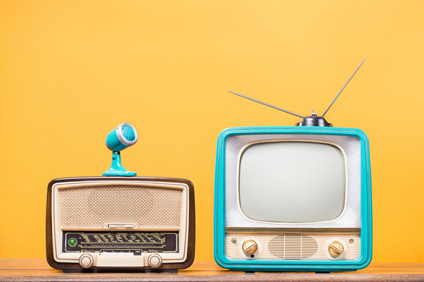 复古电视、古董木质收音机和旧麦克风前景为黄色墙壁背景。复古风格的滤镜照片图片下载