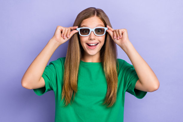 快乐的女士戴着眼镜，观看喜剧电影，背景为紫色。图片下载