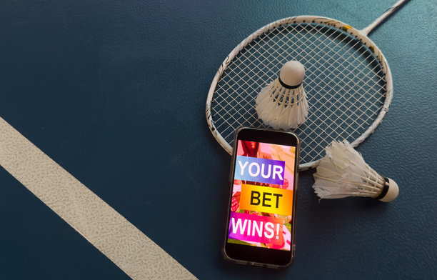 一把羽毛球拍和一部带有体育博彩的智能手机图片下载