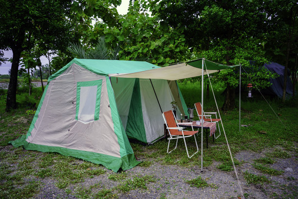 夜间露营帐篷，复古小木屋帐篷，古董灯笼，复古椅子，以及森林中木桌上的户外咖啡制作设施图片下载