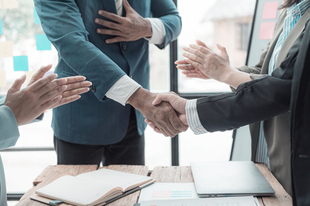 商人们手牵着手，拿着带有图形和财务图表的文件，一起看商业协议的概念，特写图片。图片下载