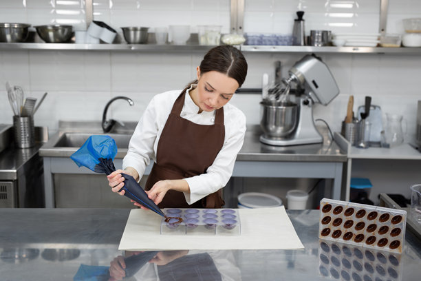 巧克力师将巧克力倒入模具中。图片下载