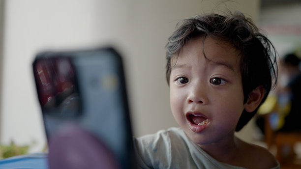 快乐的亚洲男孩在用智能手机观看和玩卡通。图片下载