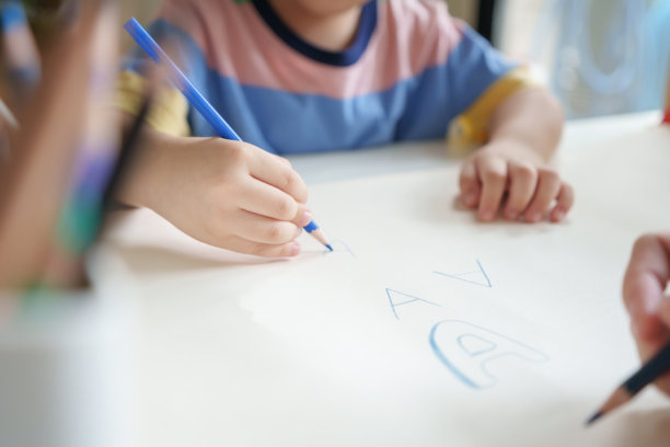 亚洲小男孩在家里和妈妈一起用彩色铅笔在纸上画画。图片下载