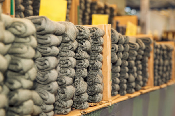仓库货架上整齐叠放的灰色袜子，多排有序的纺织品，供应概念图片下载
