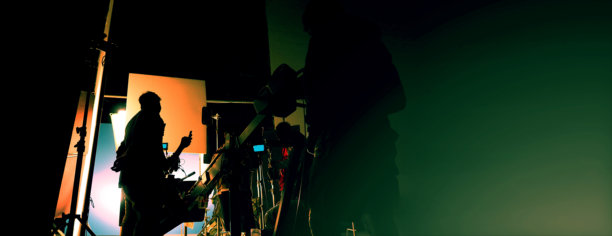 电影制作现场的剪影，展示了电影摄制组和装有电影灯光设备及蓝幕的特殊滑轨起重机上的摄像机。图片下载