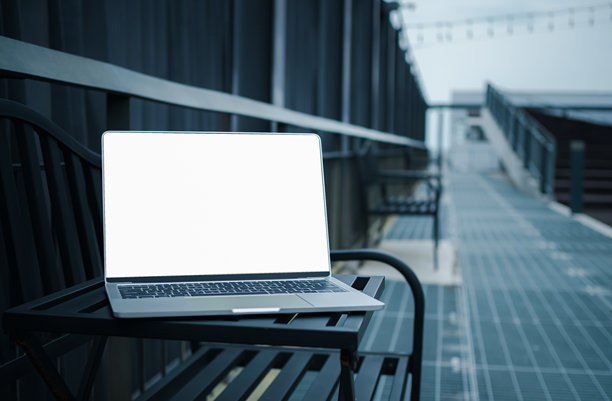 一台白色空白屏幕的笔记本电脑放在现代城市走廊旁的金属桌子上，空白的复制空间，模糊背景中的笔记本电脑，学习和办公工作的概念。图片下载