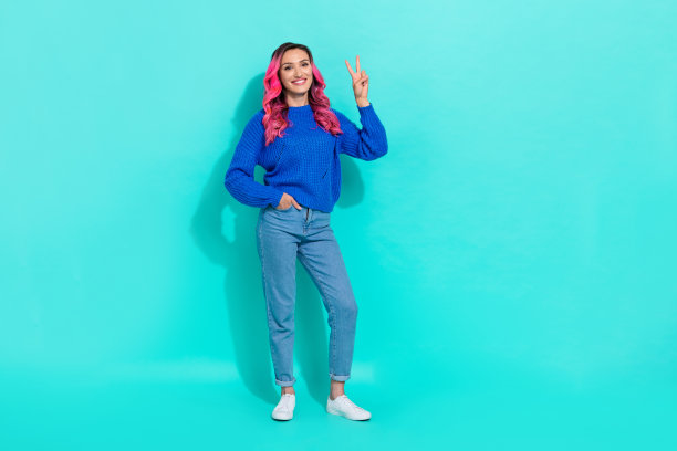 全身年轻迷人模特，奢华的卷曲粉色染发，做出和平手势，背景为青绿色。图片下载