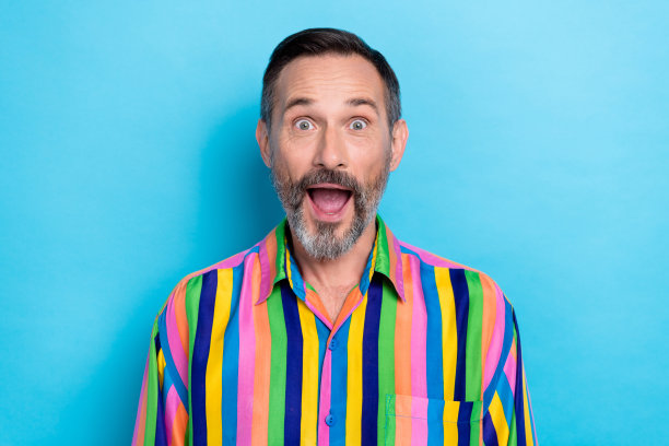 成熟男性的特写照片，灰色胡须，张嘴表现出意外反应，因大幅通货膨胀和疯狂的价格而感到震惊，昂贵的产品，背景为蓝色。图片下载