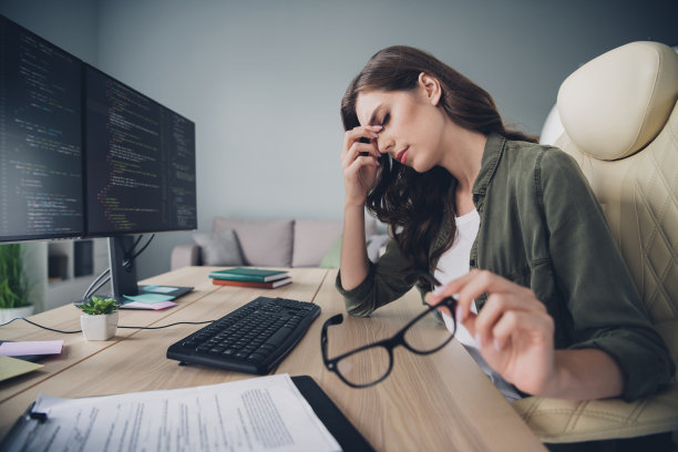 沮丧情绪的女士侧面照片，因加班而感到疲惫，正在室内工作站编写JavaScript程序。图片下载